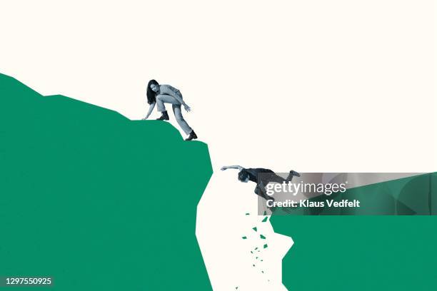 woman looking back at friend falling from cliff - menselijke relaties stockfoto's en -beelden