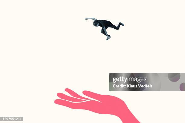 young man in mid-air falling on red hand - big small stock-fotos und bilder