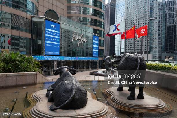 The Chinese and Hong Kong flags flutter as screens display the Hang Seng Index outside the Exchange Square complex, which houses the Hong Kong Stock...