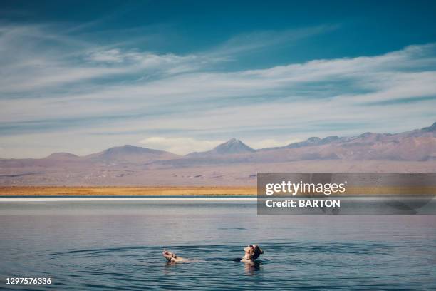 beautiful woman relaxes floating in salty lake in the atacama desert - cejar lagoon - antofagasta stockfoto's en -beelden