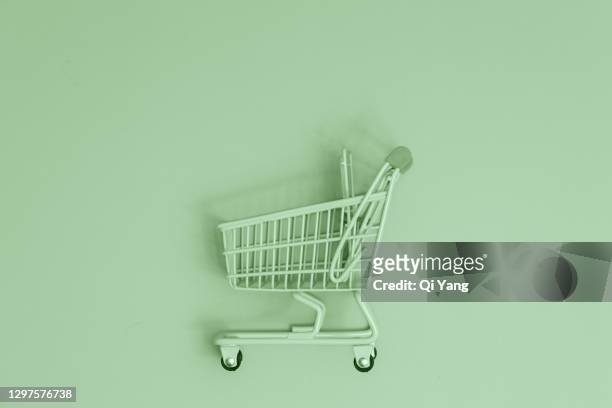 shopping cart on green background - concept store fotografías e imágenes de stock