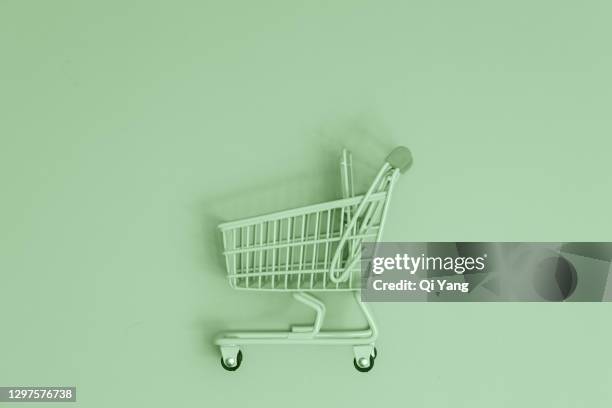 shopping cart on green background - mercado espaço de venda no varejo - fotografias e filmes do acervo