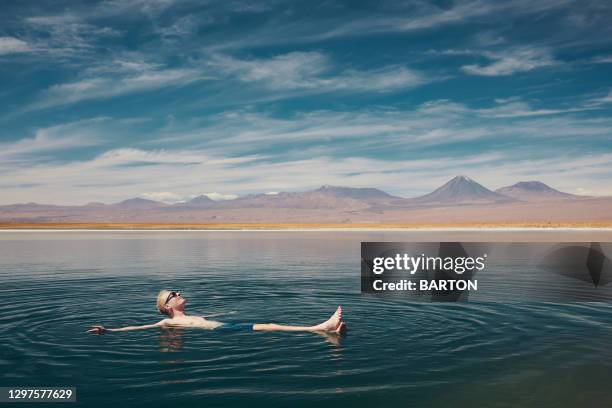 smiling, happy man, relaxes floating in salty lake in the atacama desert - san pedro de atacama bildbanksfoton och bilder