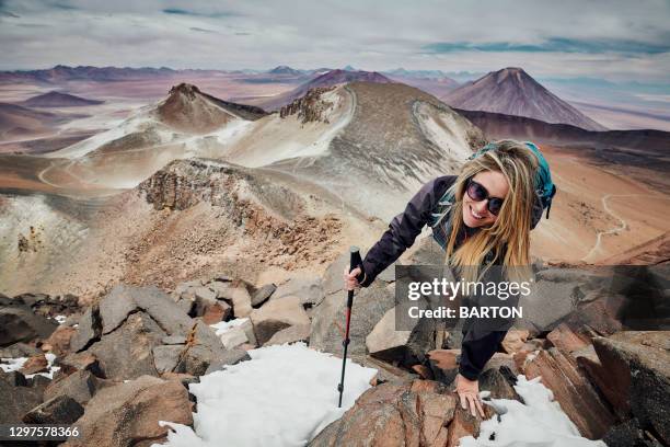 young attractive woman smiles to camera as she climbs dangerous mountain sairecabur - antofagasta fotografías e imágenes de stock