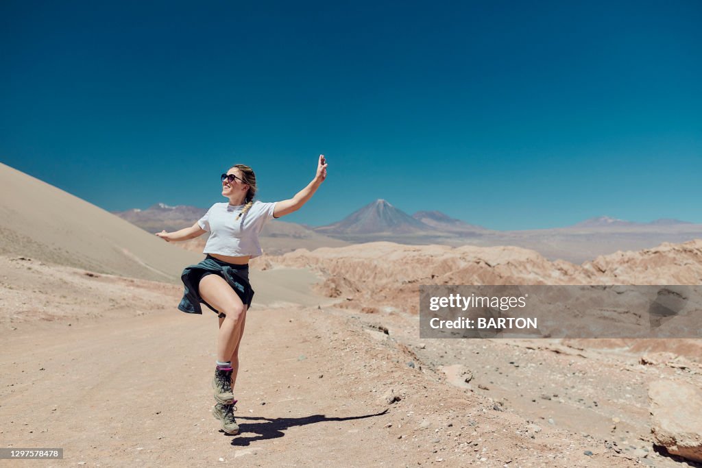 Beautiful woman smiling and dancing in the Atacma Desert