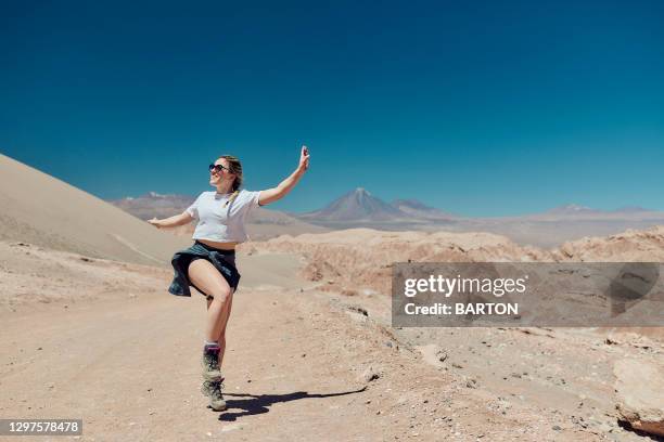 beautiful woman smiling and dancing in the atacma desert - women in daisy dukes stock pictures, royalty-free photos & images