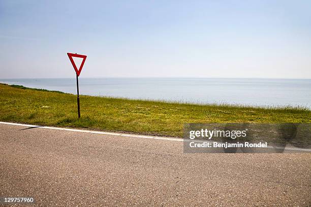 yield sign next to coastal road - caution sign traffic stockfoto's en -beelden