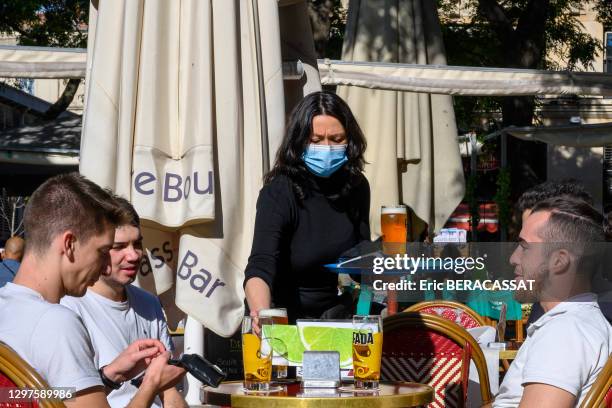 Serveuse avec un masque servant des bières à des jeunes gens à une terrasse de café, place Jean Jaurès, 10 octobre 2020, Montpellier, France.