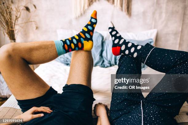 legs of couple lying in bed wearing dotted socks - strümpfe stock-fotos und bilder