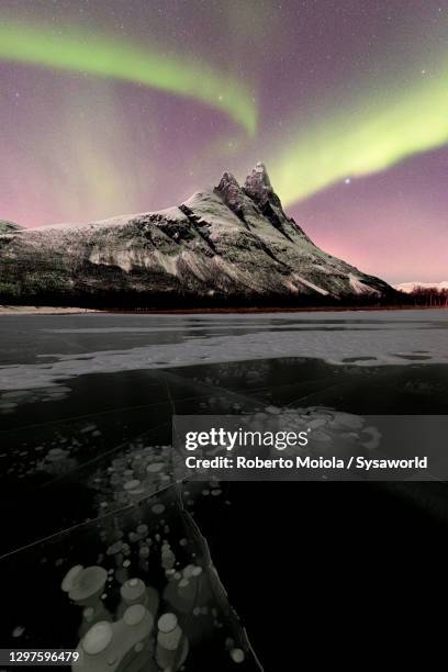 ice bubbles and mountains during aurora borealis, norway - noord stockfoto's en -beelden