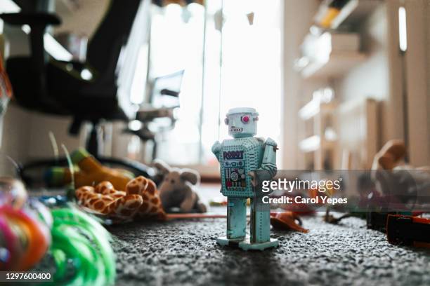 toy robot surrounded by other toys on the carpet in child bedroom - opwindspeeltje stockfoto's en -beelden