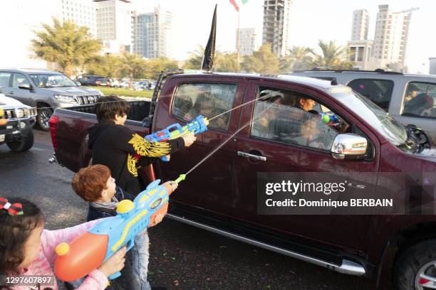 Enfants lançant de l'eau sur les voitures et passants lors de la fête nationale, 25 février 2019, Koweït city.