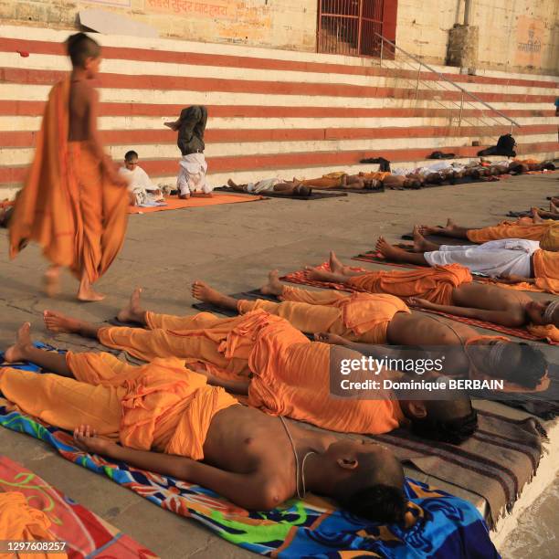 Des écoliers brahmanes allongés par terre suivent un cours de yoga, 27 avril 2019, Varanasi , Inde.