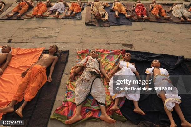 Des écoliers brahmanes allongés par terre suivent un cours de yoga, 27 avril 2019, Varanasi , Inde.