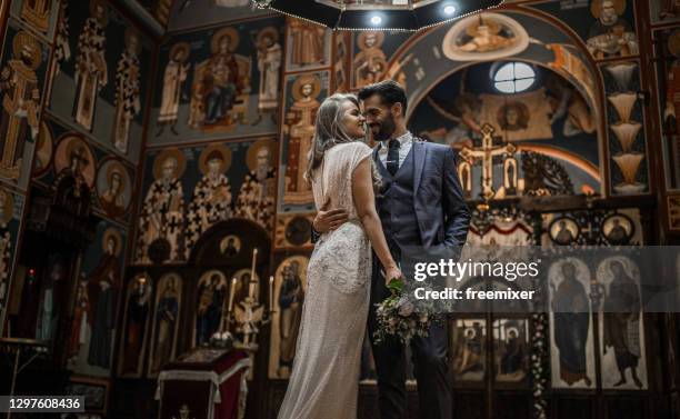 smiling couple standing in church face to face while embracing each other - married church stock pictures, royalty-free photos & images