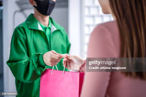 food delivery man wearing mask handing plastic bags shopping online from food shop to client service customer front house, coronavirus covid19 new normal lifestyle. - shopping list stock pictures, royalty-free photos & images