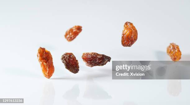 flying red grape raisins in mid air in white background - rosine stock-fotos und bilder