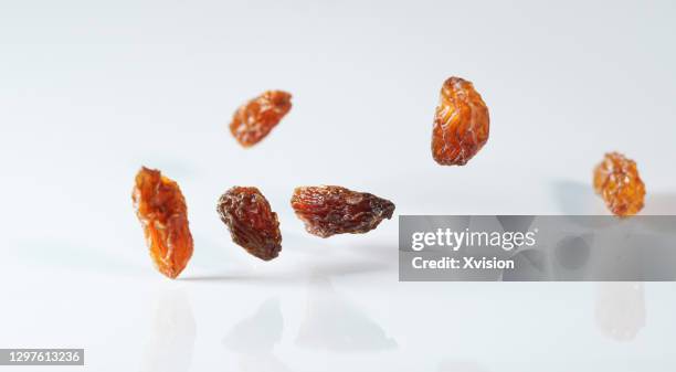 flying red grape raisins in mid air in white background - raisin stock pictures, royalty-free photos & images