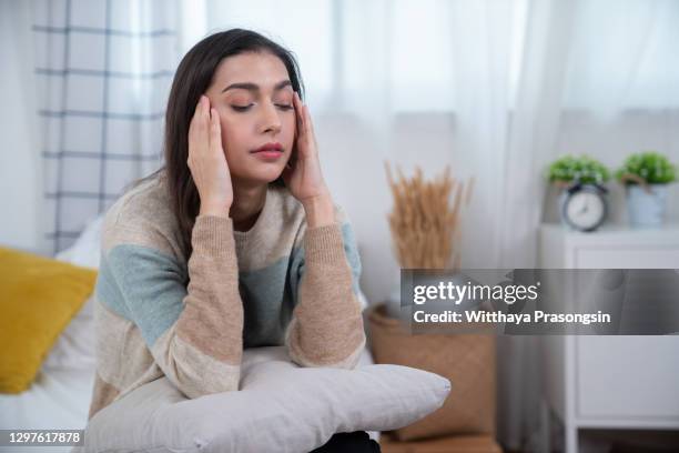 woman suffering from stress or a headache grimacing in pain - hoofdpijn vrouw stockfoto's en -beelden