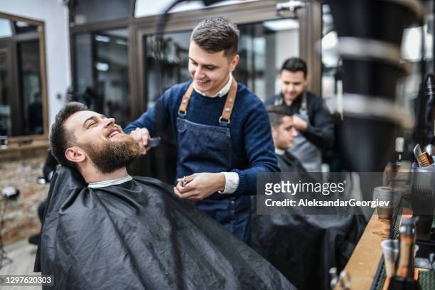 barbiere sorridente che pettina il taglio di capelli del cliente - barber shop foto e immagini stock