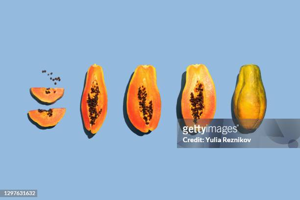 repeated halved papaya fruit on the blue background - papaya stock-fotos und bilder