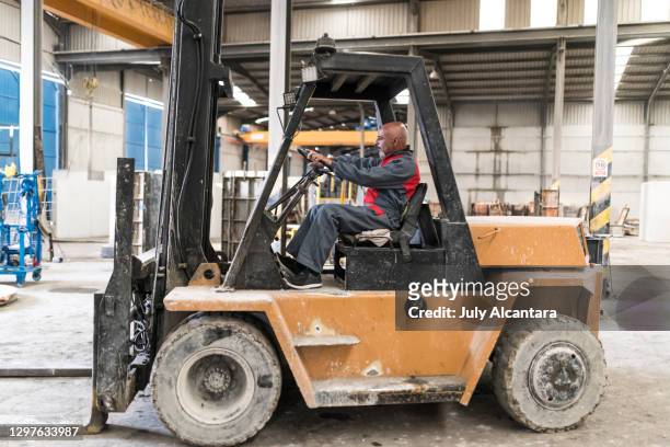55-60 jahre alter mann fährt gabelstapler in betonfabrik. cordoba, spanien. - 55 years old stock-fotos und bilder