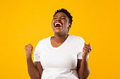 Joyful Black Woman Shouting Shaking Fists Posing Over Yellow Background