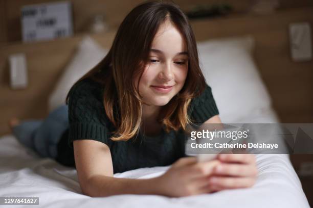 a 15 years old girl looking at her phone at home - 14 15 years stock-fotos und bilder