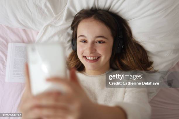 a 15 years old girl looking at her phone at home - 14 15 years girl stock pictures, royalty-free photos & images
