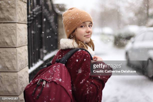a girl going to the school in a snowy street - winterjacke stock-fotos und bilder