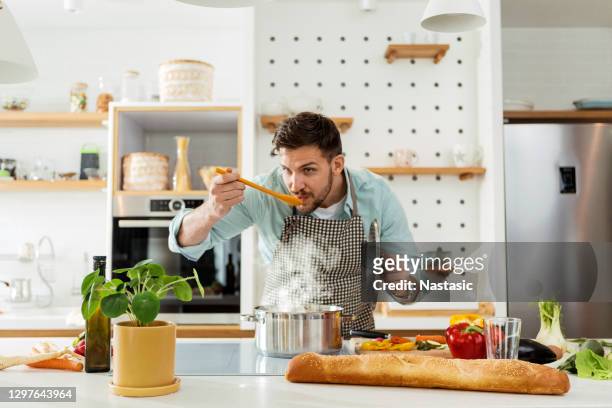 mann in der küche kochprobe - schmecken stock-fotos und bilder