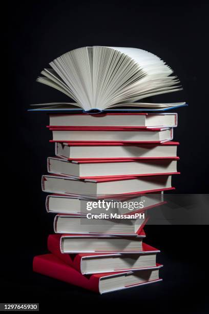 light blue hard-covered book open at the top of a pile of red books - bookshelf foto e immagini stock