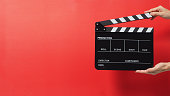 Hand is holding black Clapper board or Clapperboard or movie slate. it use in video production ,film, cinema industry on red background.