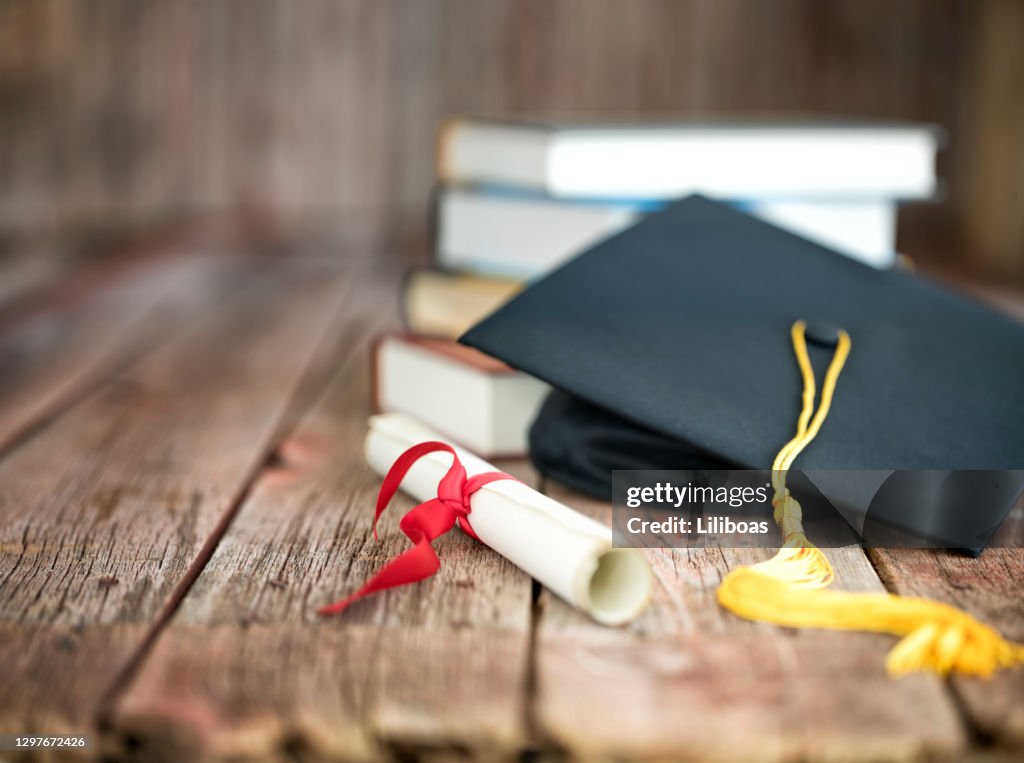 Berretto di laurea e concetto di diploma su sfondo legno