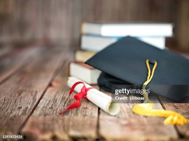 berretto di laurea e concetto di diploma su sfondo legno - laureate foto e immagini stock