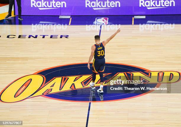 Stephen Curry of the Golden State Warriors standing on the Oakland logo at center court reacts to a teammate scoring and getting fouled against the...