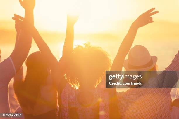 gruppe von freunden sitzen am strand bei sonnenuntergang /sonnenaufgang. - sunrise beach stock-fotos und bilder