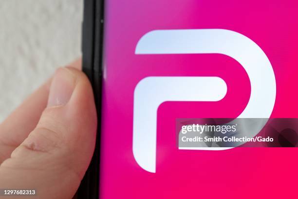 Illustrative image of human hand with mobile device showing logo for the social media platform Parler, Lafayette, California, January 21, 2021.