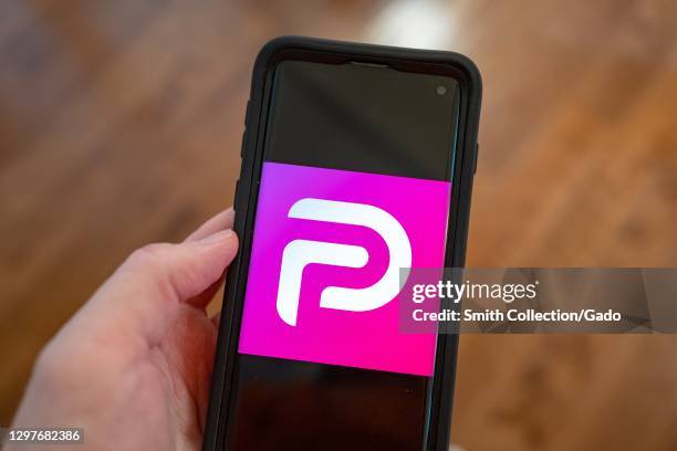 Illustrative image of human hand with mobile device showing logo for the social media platform Parler, Lafayette, California, January 21, 2021.