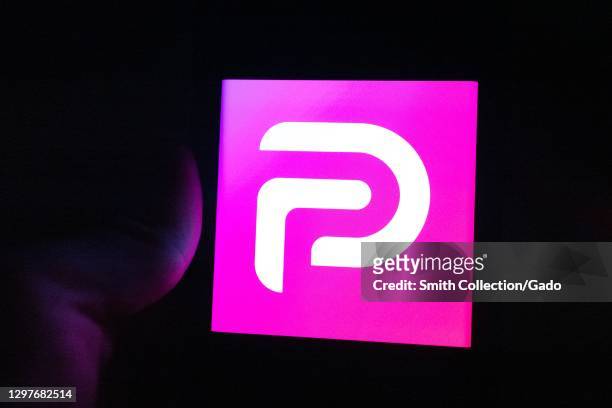 Illustrative image of human hand with mobile device showing logo for the social media platform Parler, Lafayette, California, January 21, 2021.