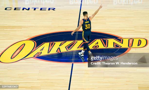 Stephen Curry of the Golden State Warriors standing on the Oakland logo at center court reacts to a teammate scoring and getting fouled against the...