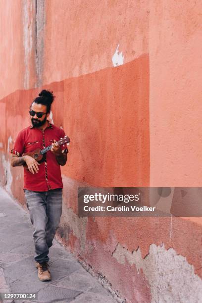 man playing the ukulele walking down the street - enmansband bildbanksfoton och bilder