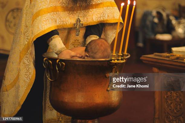 priest watering the baby, baptism - catholic baptism - fotografias e filmes do acervo