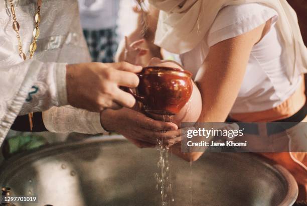 priest watering the baby, baptism - catholic baptism stock-fotos und bilder