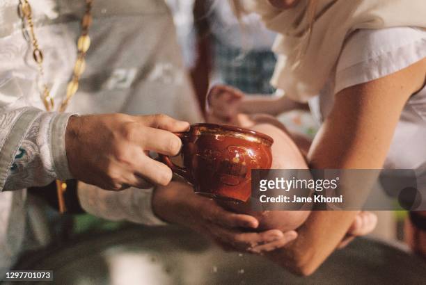 priest watering the baby, baptism - catholic baptism stock-fotos und bilder