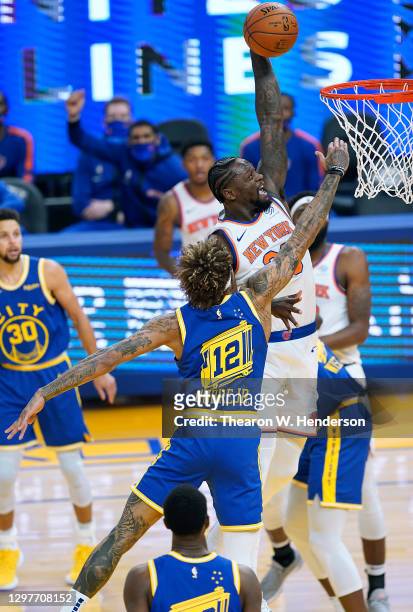 Julius Randle of the New York Knicks goes up to attempt a slam dunk over Kelly Oubre Jr. #12 of the Golden State Warriors during the first half of an...