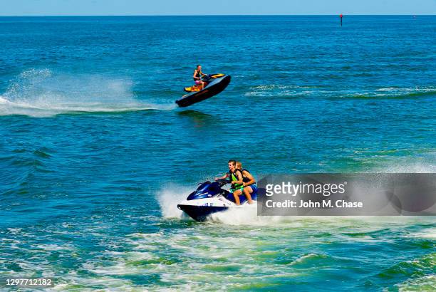 los hombres jóvenes saltan las olas en un jetski - jet boat fotografías e imágenes de stock