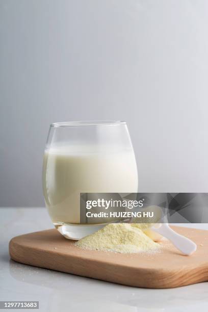 glass of milk with powdered milk and spoon - protein powder stock-fotos und bilder