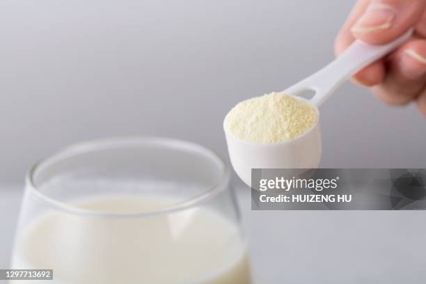 glass of milk with powdered milk and spoon - proteina foto e immagini stock