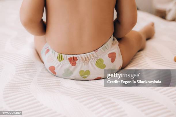 back view of charming baby sitting on the bed. - kids in undies stock-fotos und bilder